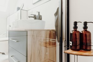 Bathroom features a large vessel sink, metal shelf, and ample storage.