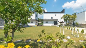 Une maison moderne avec une pelouse bien entretenue, un but de football et un espace de jeux équipé de jouets.