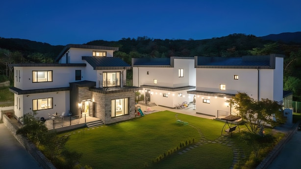 A modern multi-story house with a well-maintained lawn and outdoor seating area. - Gyeongju Blibli Poolvilla (Gyeongju)