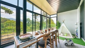 A dining area with a view of the countryside, a grill, and a teepee. - Gyeongju Blibli Poolvilla (Gyeongju)