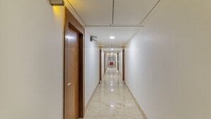 Un pasillo largo y estrecho con una puerta de madera a la izquierda y un armario rojo a lo lejos.