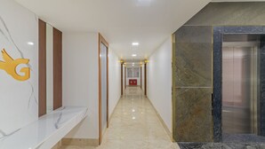 Un pasillo con un mostrador de recepción de mármol, un marco de puerta de madera y un suelo de mármol que conduce a un ascensor.