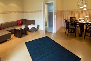 A living room with a sofa, a coffee table, and a dining area with chairs and a table.
