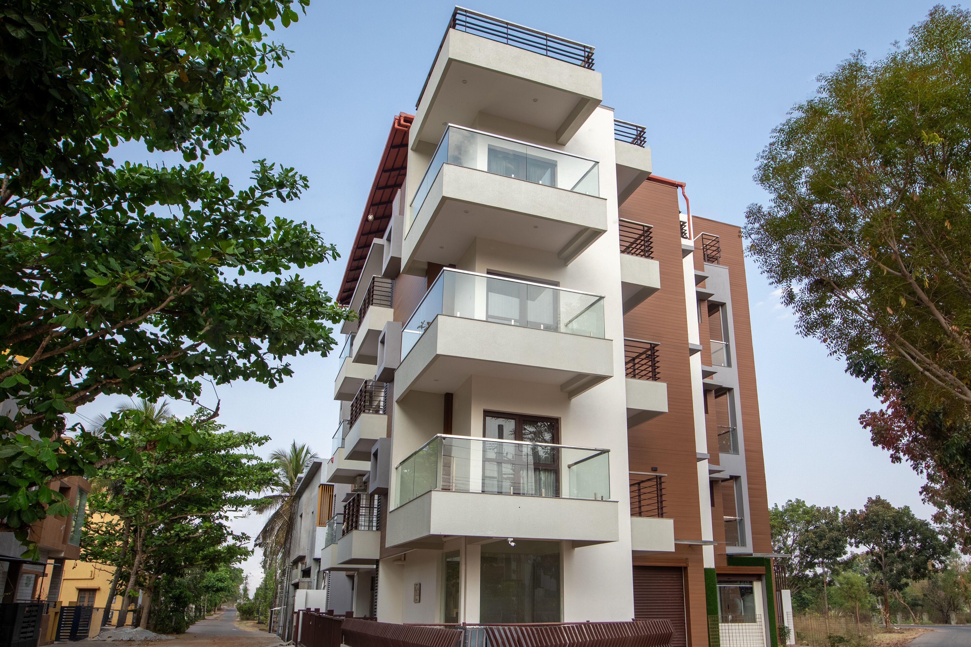 Un immeuble résidentiel à plusieurs étages, doté de balcons, d’une entrée sécurisée et entouré de verdure.