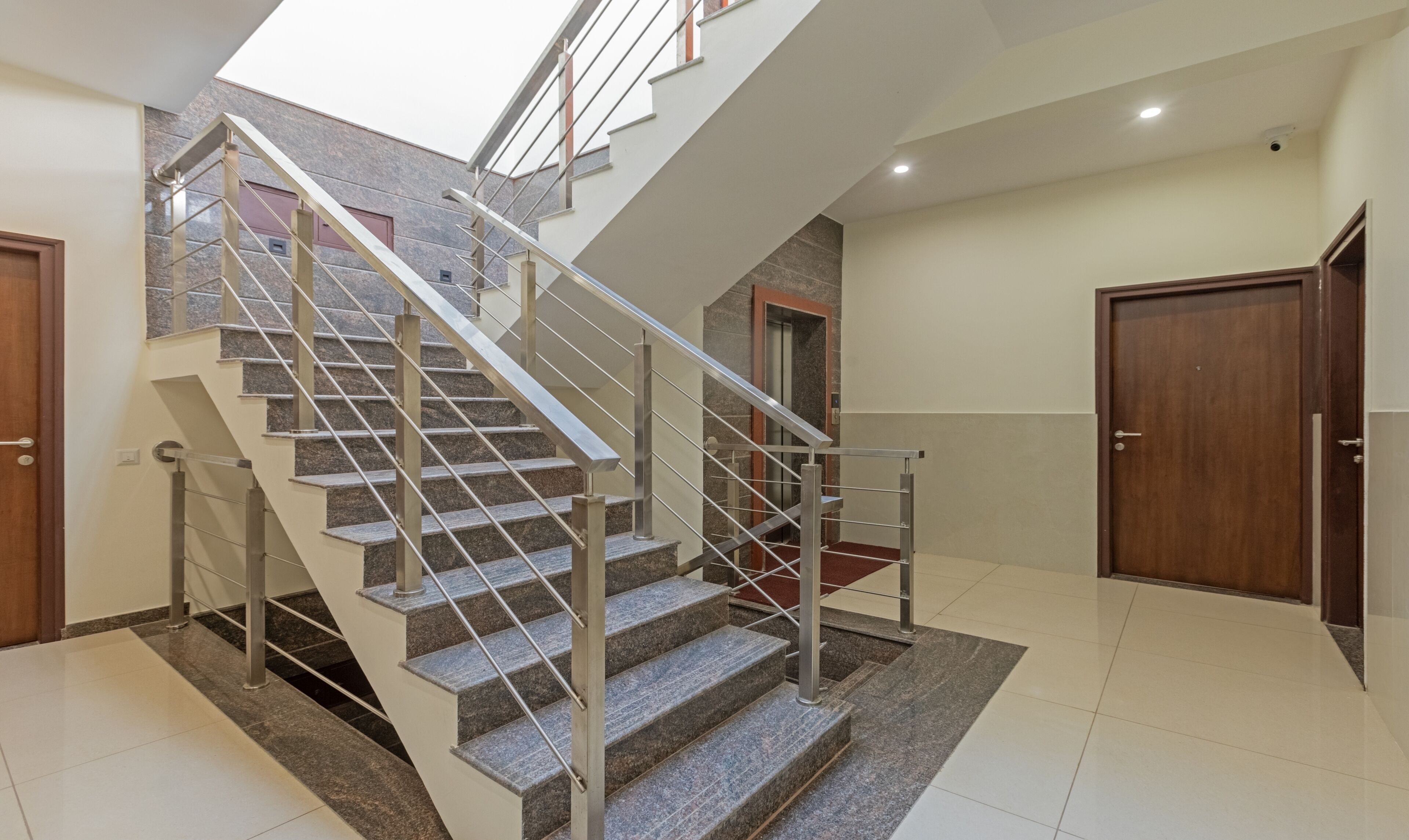 A modern staircase with metal railings and granite steps, leading to an upper level.
