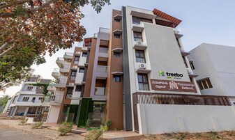 Um edifício de vários andares com varandas, aparelhos de ar condicionado e uma placa com a inscrição 'Treebo trend Samavaya Retreat'.