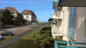 Um bairro residencial com uma estrada, carros estacionados e vista para o mar.