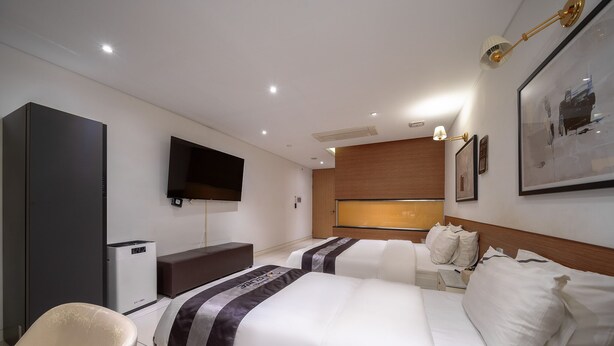 Habitación de hotel con dos camas, televisión, escritorio y un ventanal grande.