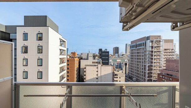 A high-rise building with multiple balconies, a clear sky, and a cityscape view. - Apartment Hotel 11 Shinsaibashi II (Osaka)