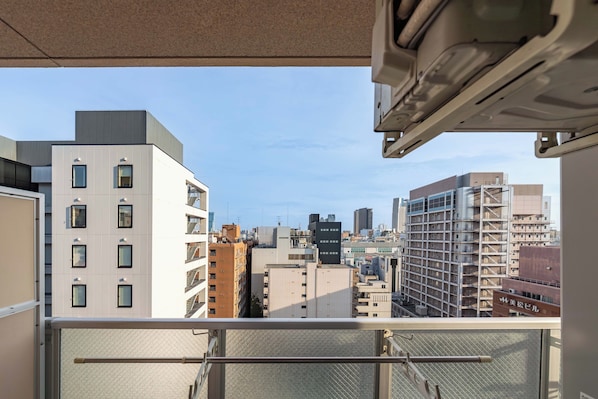 Un edificio de gran altura con varios balcones, cielo despejado y vista panorámica de la ciudad.