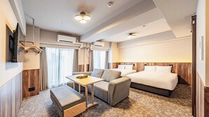 Ein Hotelzimmer mit Bett, Sofa, Tisch und Fernseher.
