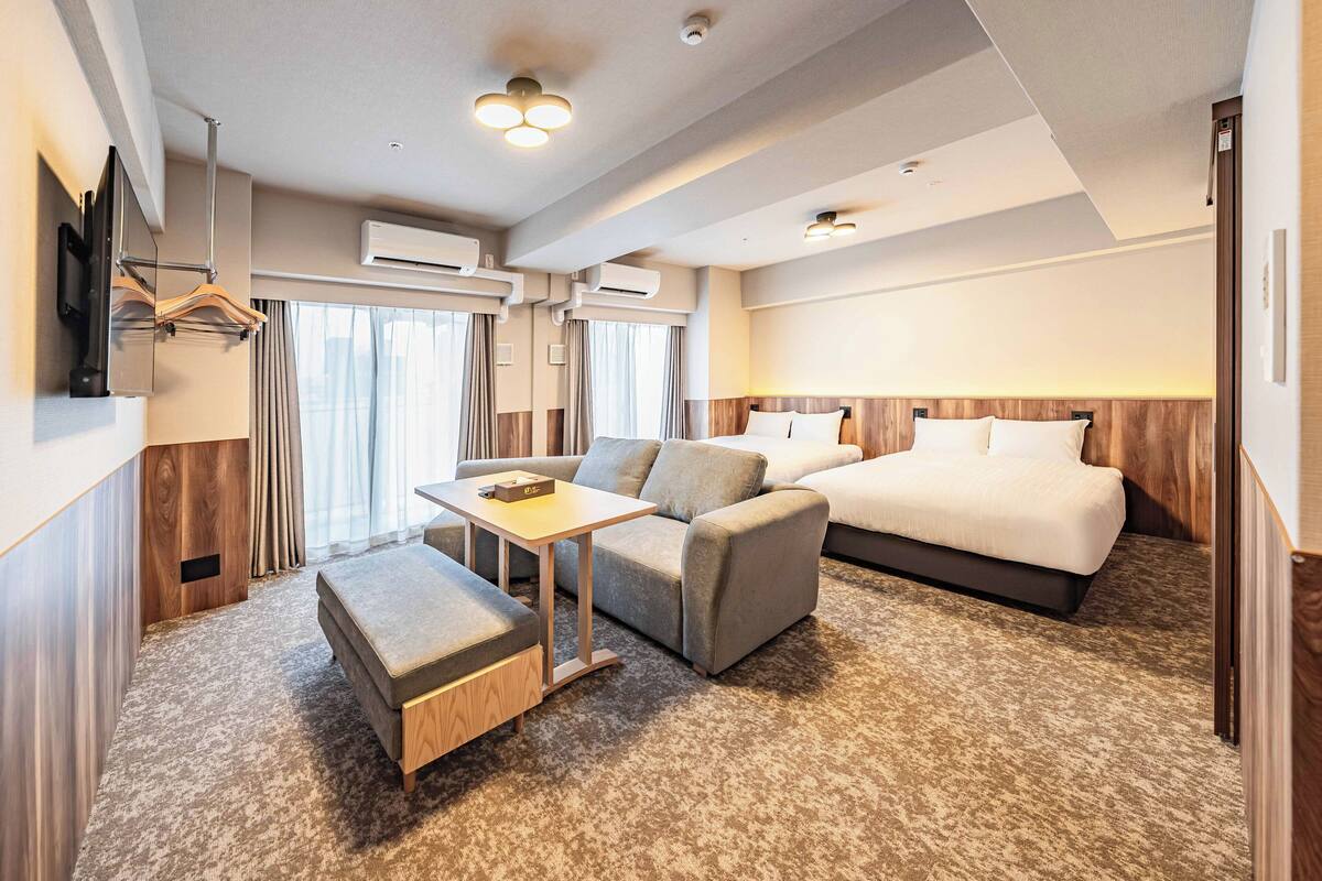 Une chambre d’hôtel avec un lit, un canapé, une table et un téléviseur.
