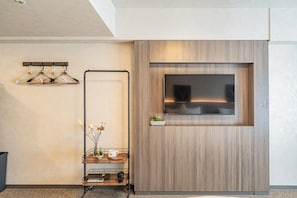 Ein modernes Interieur mit einer Wandpaneelaus Holz, einem an der Wand montierten Fernseher, einem Kleiderhaken und einer kleinen Pflanze auf einem Regal.