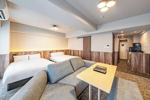 Une chambre d’hôtel avec deux lits, un canapé, une petite table et une kitchenette.