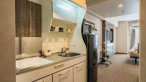 A modern kitchen with white cabinets, a black refrigerator, and a stainless steel sink. - Apartment Hotel 11 Shinsaibashi II (Osaka)