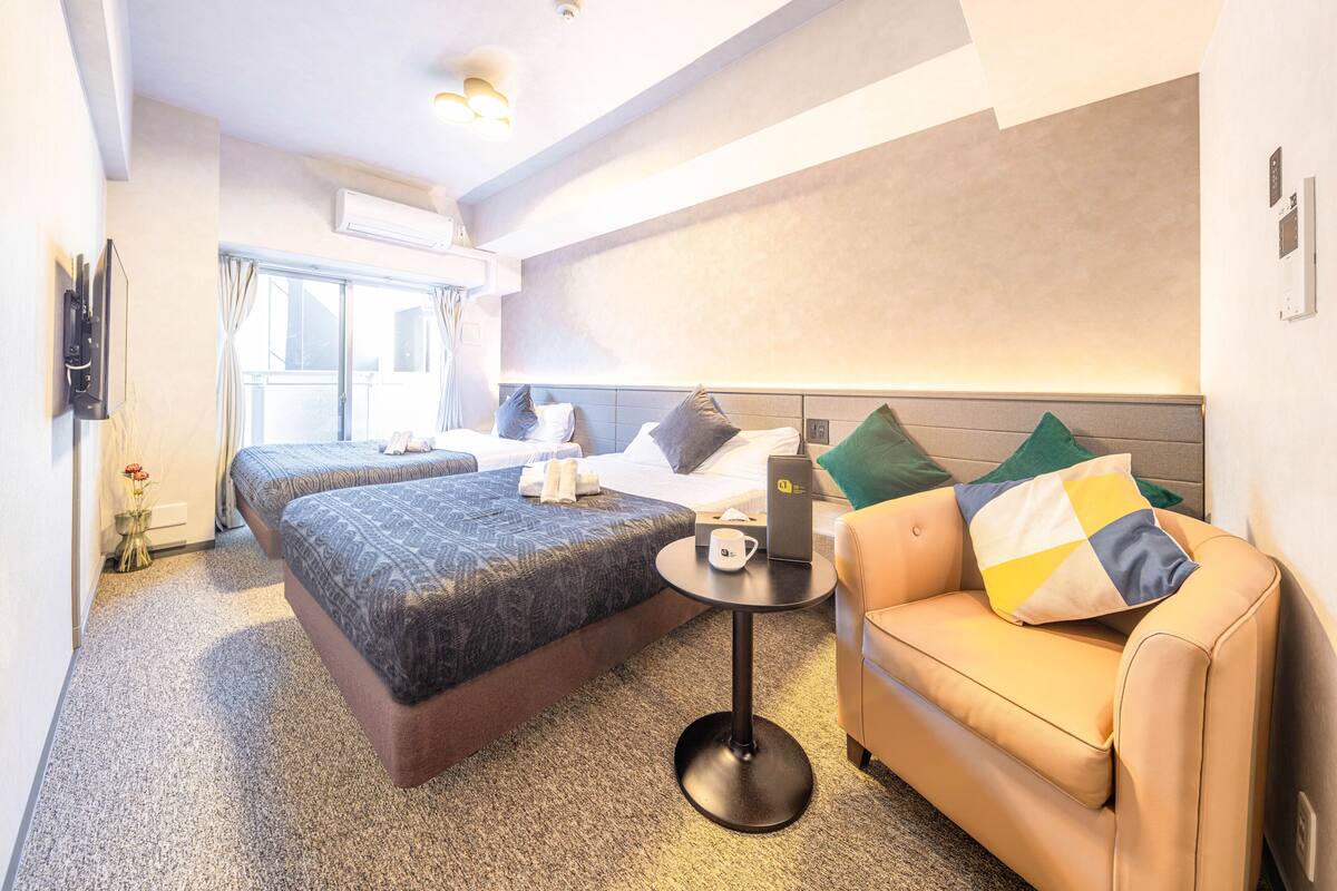 Une chambre d’hôtel avec deux lits, un canapé, une petite table et un téléviseur.