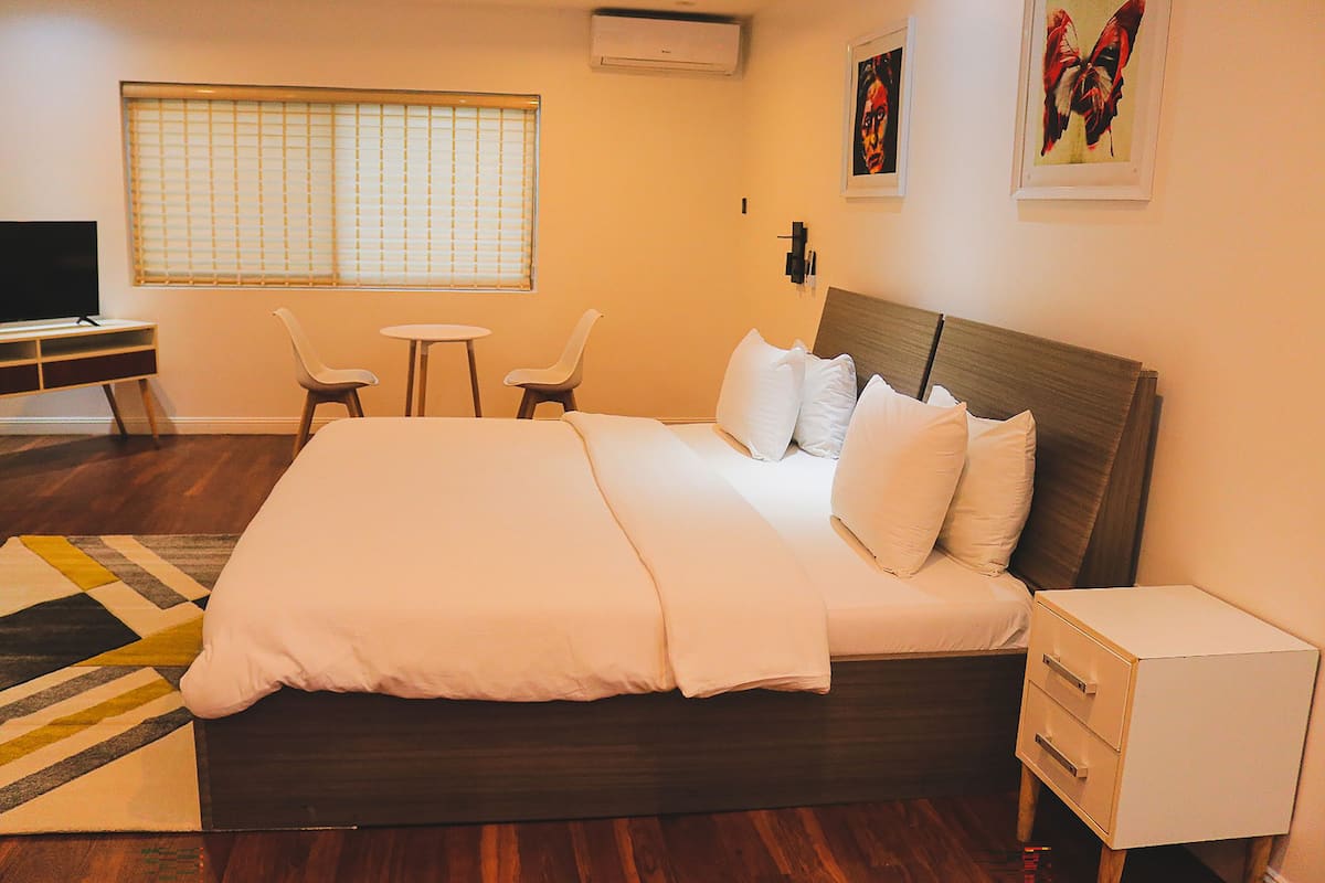 A hotel room with a large bed, bedside tables, a desk with a chair, and a TV.