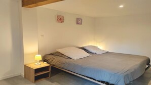 Un dormitorio con una cama, una mesita de noche con lámpara y dos adornos en la pared.
