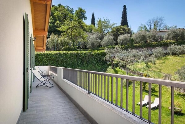 A balcony with a view of a well-maintained garden and trees. - The essence apartments n15 (Malcesine)