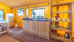 A compact kitchen with a wooden island, a refrigerator, and a window with a view. - Tenuta Regina Agriturismo e Glamping (Palazzolo dello Stella)