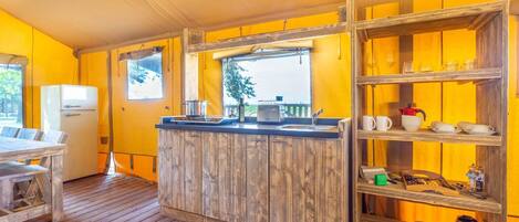 Une cuisine compacte avec un îlot central en bois, un réfrigérateur et une fenêtre donnant sur un beau paysage.