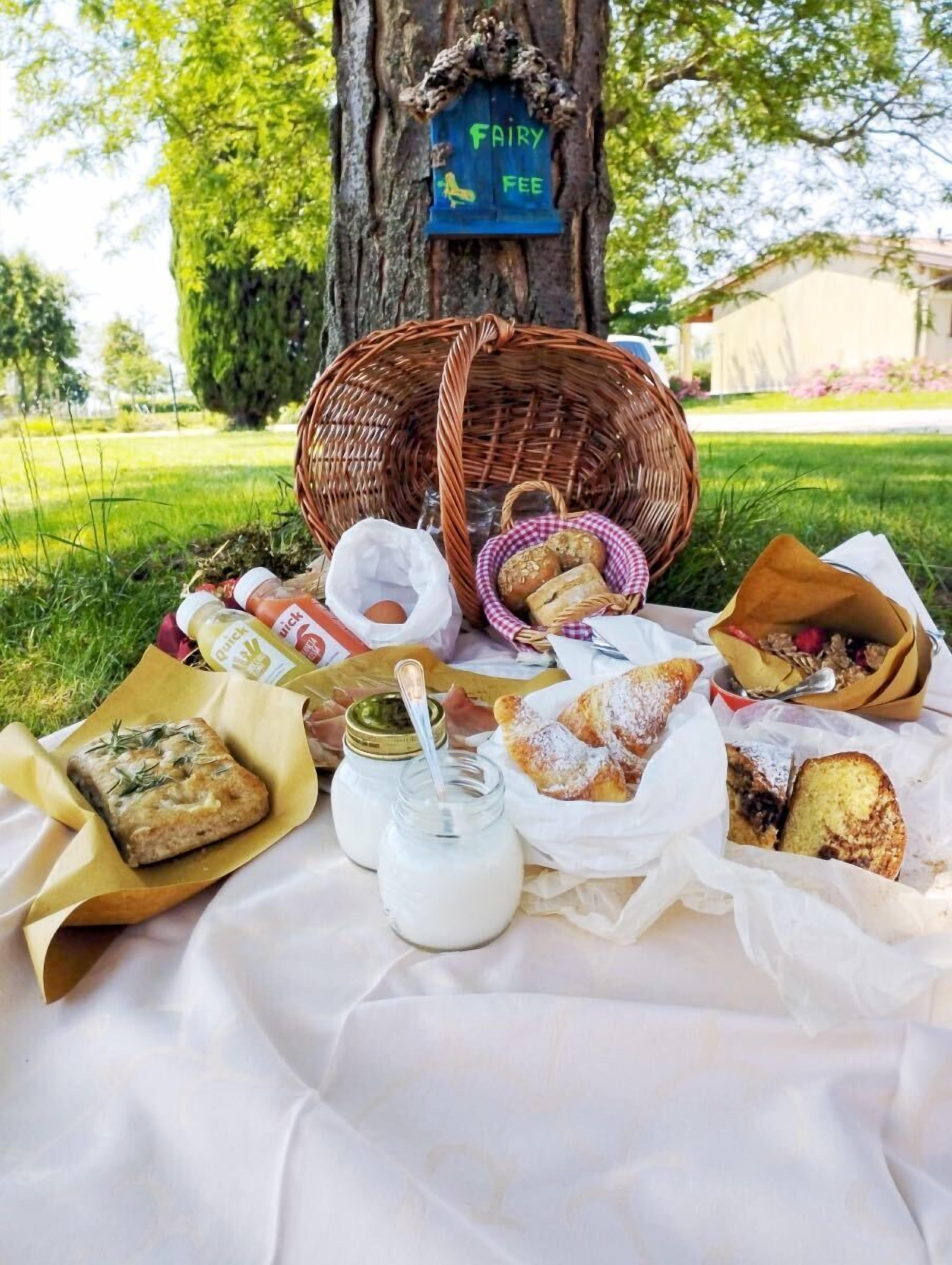 En picknickplats med matvaror, en korg och en skylt på ett träd.