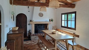 Una cocina rústica con una mesa de madera, bancos, chimenea y un ventanal grande.