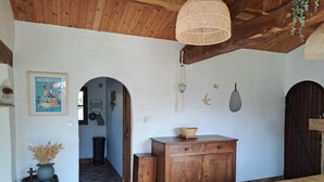 Una habitación rústica con techo de madera, un mueble grande de madera, una mesa de comedor y un cartel antiguo en la pared.