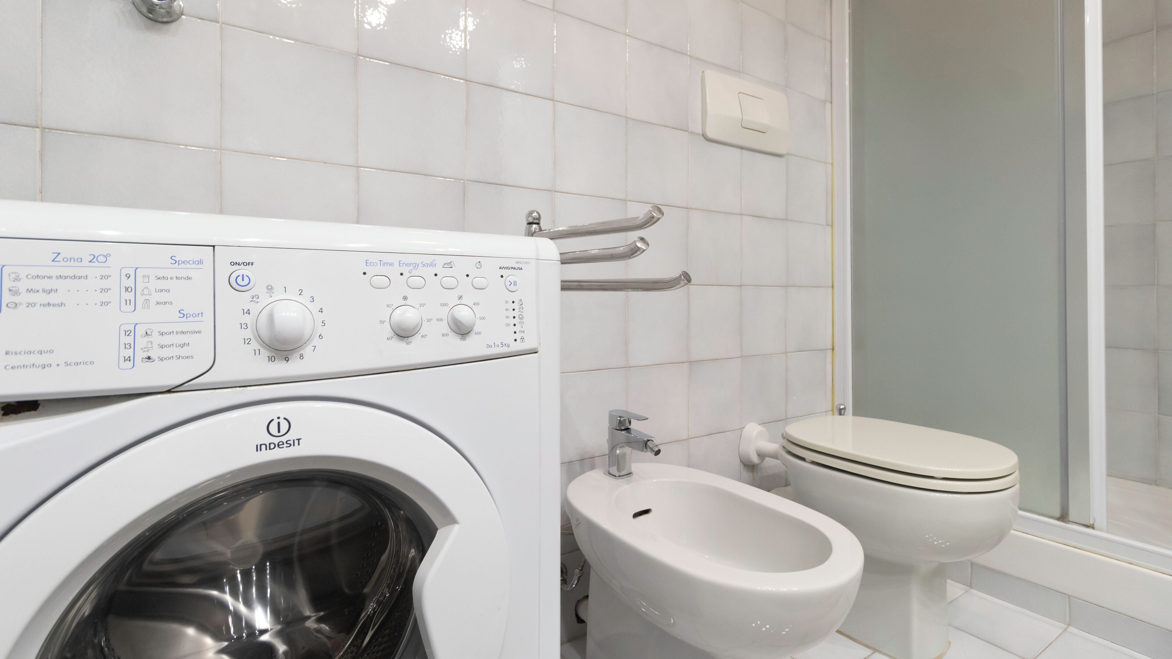 A modern bathroom with a washing machine, bidet, and toilet.