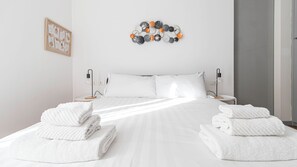 A hotel room with a neatly made bed, two bedside tables with lamps, a wall-mounted light fixture, and a framed picture on the wall. - Italianway Comfort - Della Palla 5 (Milan)