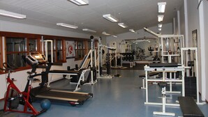 Un gimnasio con cintas de correr, máquinas de pesas y pelotas de ejercicio.