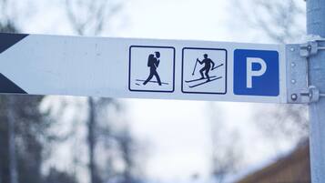 A directional sign with symbols for walking and skiing, and a parking symbol.