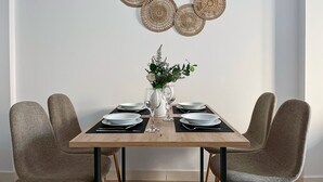 A dining table set with plates, cutlery, and a vase with flowers. - Estudio con Cama Doble - Picú Home (Málaga)