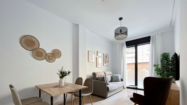 A modern living room with a dining area, a sofa, a coffee table, and a TV. - Estudio con Cama Doble - Picú Home (Málaga)