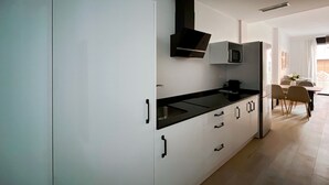 A modern kitchen with white cabinets, black countertops, and a microwave. - Estudio con Cama Doble - Picú Home (Málaga)
