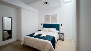 A modern bedroom with a large bed, a mirror, and artwork on the wall. - Estudio con Cama Doble - Picú Home (Málaga)