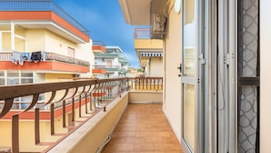 Ein Balkon mit Fliesenboden, Holzwertlauf und Blick auf angrenzende Gebäude.