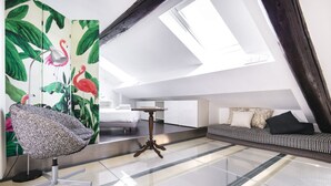 A modern loft bedroom with a skylight, a large mirror, a patterned chair, a sofa, and a small table. - Easylife - Spacious apartment in Porta Romana (Milano)