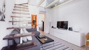 A modern living room with a grey sofa, a wooden coffee table, and a TV on a white cabinet. - Easylife - Spacious apartment in Porta Romana (Milano)