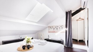 A modern bedroom with a skylight, a bed with a tray of items, a radiator, and a wardrobe. - Easylife - Spacious apartment in Porta Romana (Milano)