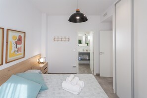 Et moderne soveværelse med seng, sengebord, lampe og kunstværk.