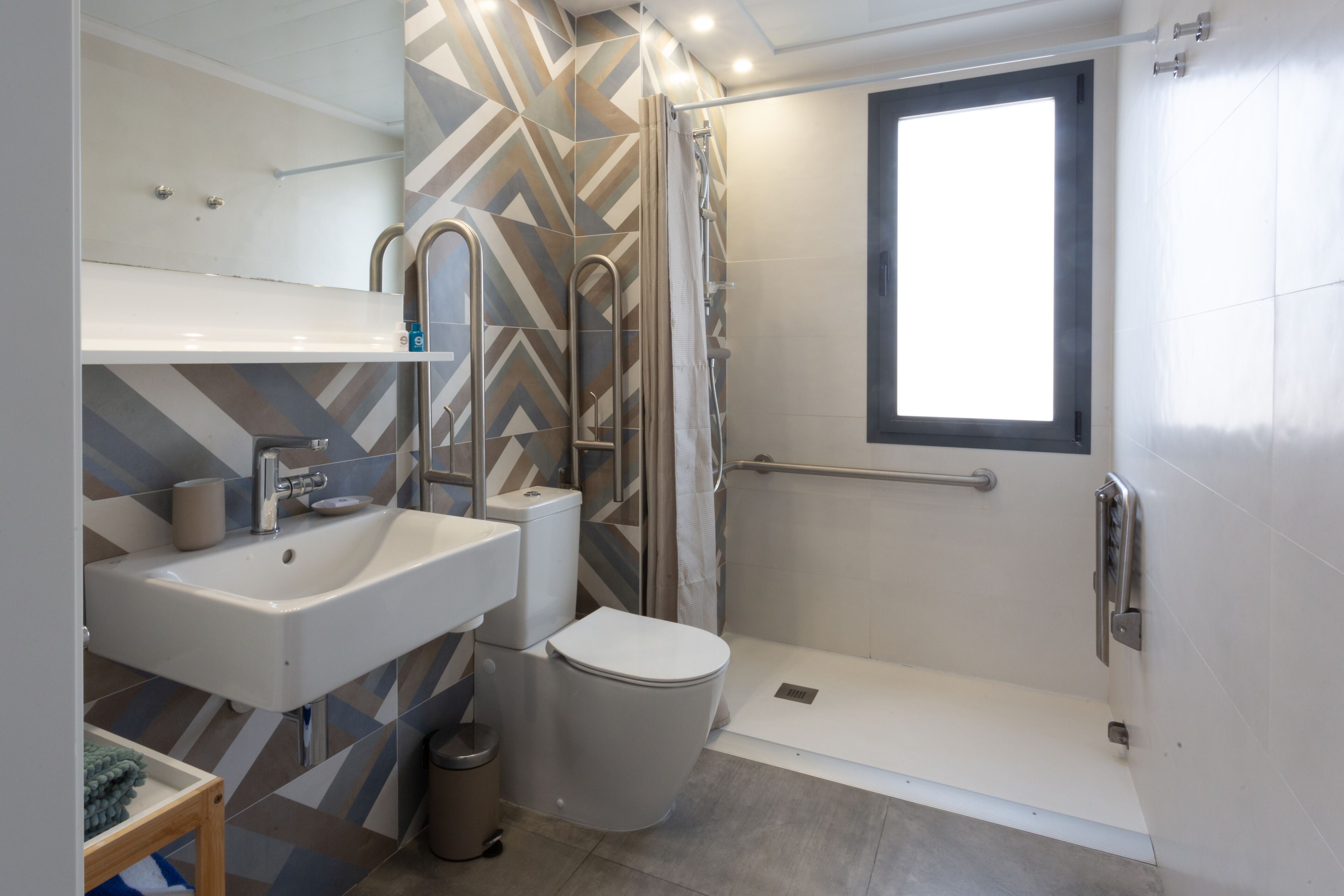 Un baño moderno con ducha, inodoro, lavamanos y ventana.