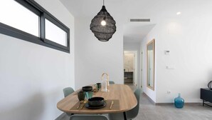 Un espace repas moderne avec une table en bois, des chaises et un luminaire suspendu.