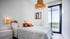 A bedroom with a bed, bedside table, and a view through a large window. - [P2L02] (Oliva)