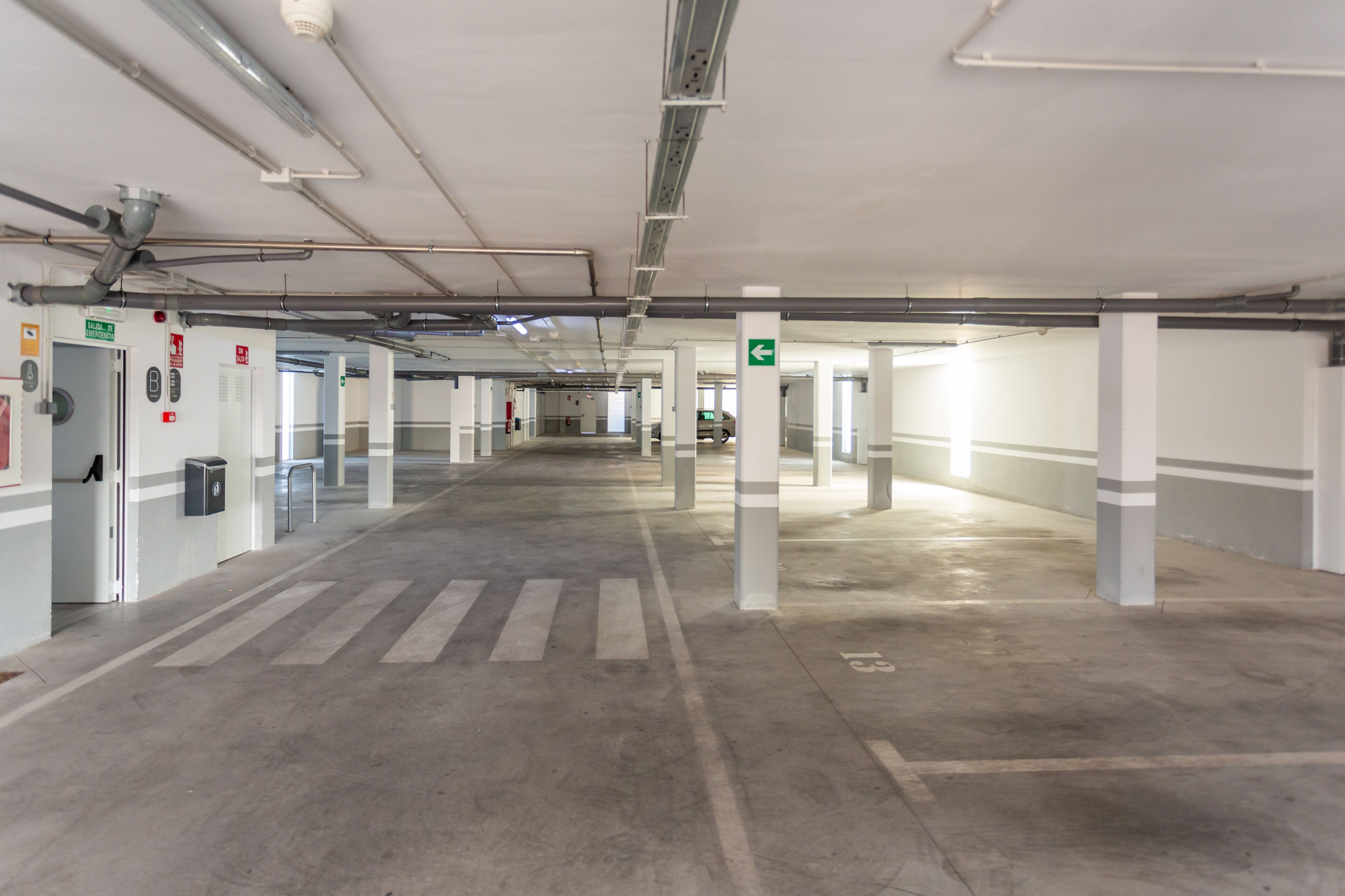 A multi-level parking garage with clear signage, emergency equipment, and a clean, well-lit environment.