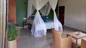 A bedroom with a canopy bed, a small table, a chair, and a potted plant. - ilasan cottage (Tomohon)