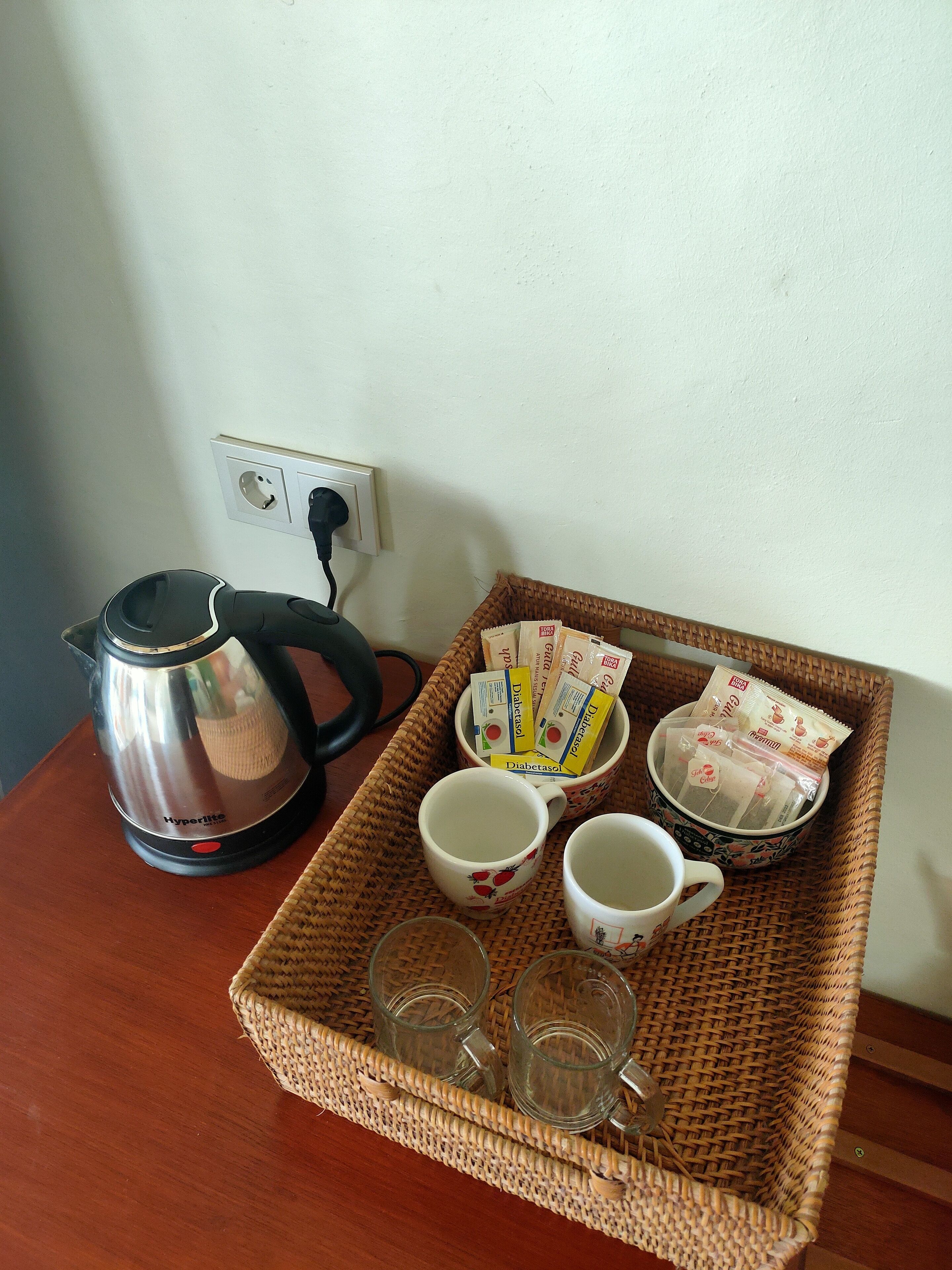 A tray with a kettle, cups, and tea packets on a table.