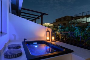 Un jacuzzi en la azotea con vistas a un paisaje urbano al atardecer.