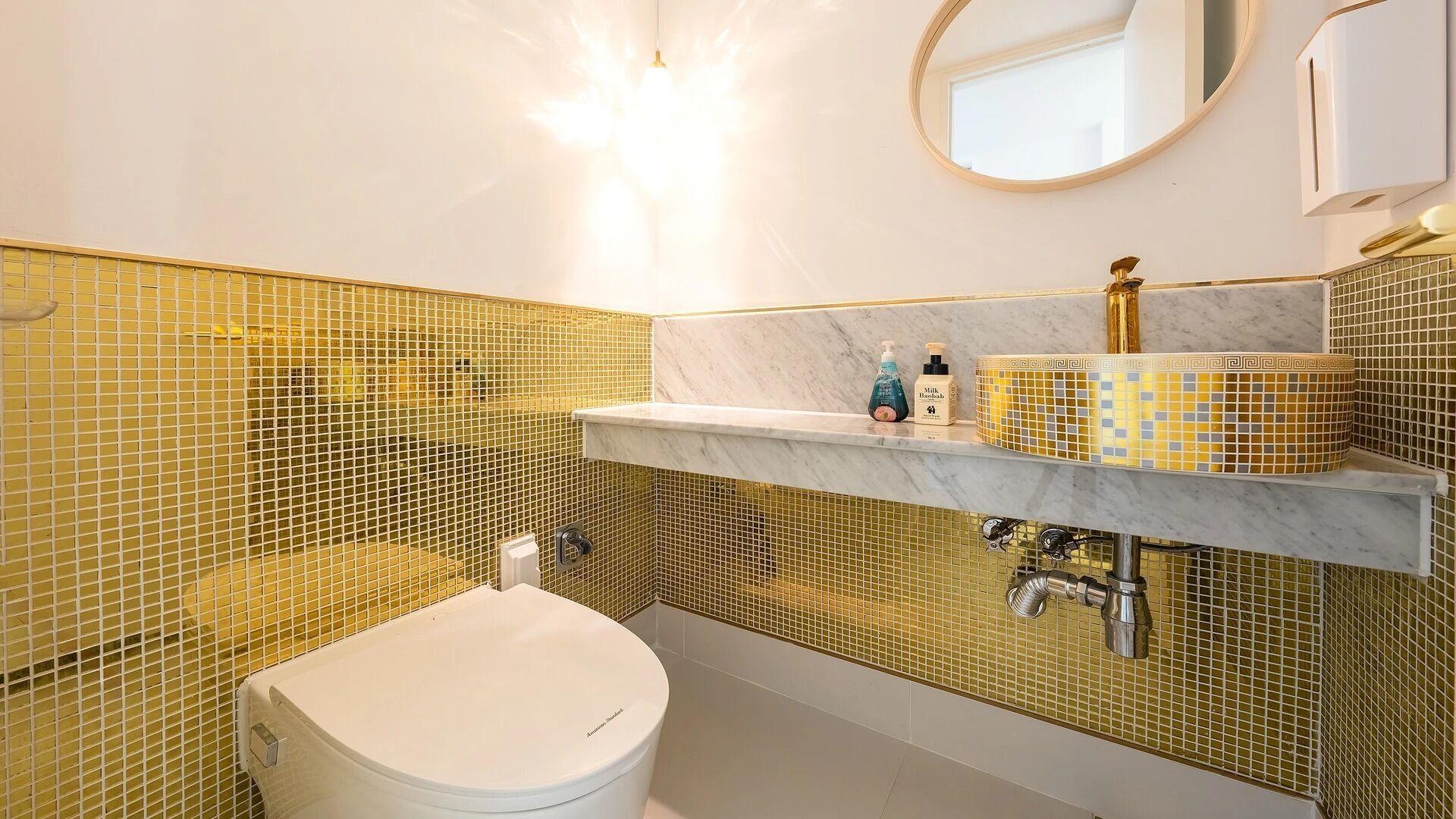 Un baño con inodoro blanco, lavamanos de mármol y un espejo.