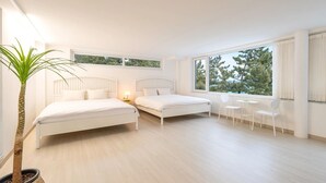 Une chambre avec deux lits, une plante en pot, une petite table et des chaises.
